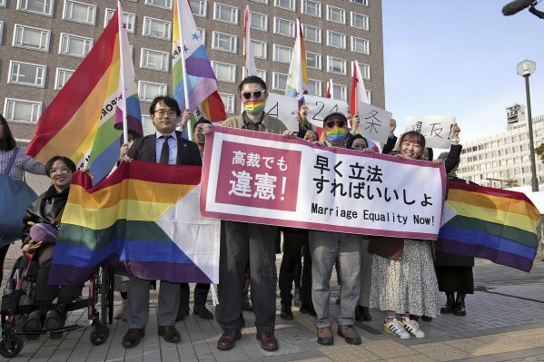 Plaintiffs and others shows a banner in front of Sapporo Hight Court in Sapporo, Hokkaido, northern Japan Thursday, March 14, 2024. A banner reads 