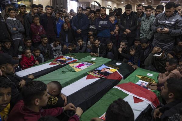 FILE, Mourners gather around the coffins of four out of eight Palestinian migrants who died off the Tunisian coast, during their funeral at a mosque in Rafah in the southern Gaza Strip, Sunday, Dec. 18, 2022. As a rising number of Gazans are drowning in the sea en route to a better life in Europe, Gaza's Hamas rulers are moving to comfortable life in upscale Middle East hotels, prompted a rare outpouring of anger at home, where the economy collapses and 2.3 million people remain effectively trapped in the tiny, conflict-scarred territory. (AP Photo/Fatima Shbair, File)