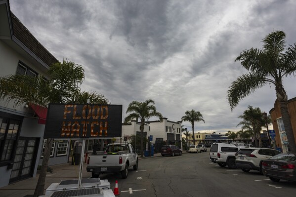 A sign warns of potential flooding in Capitola Village Wednesday, Jan. 31, 2024, in Capitola, Calif. An atmospheric river is set to make its way into Northern California, bringing warnings of heavy rain, possible flooding and high winds.(AP Photo/Nic Coury)