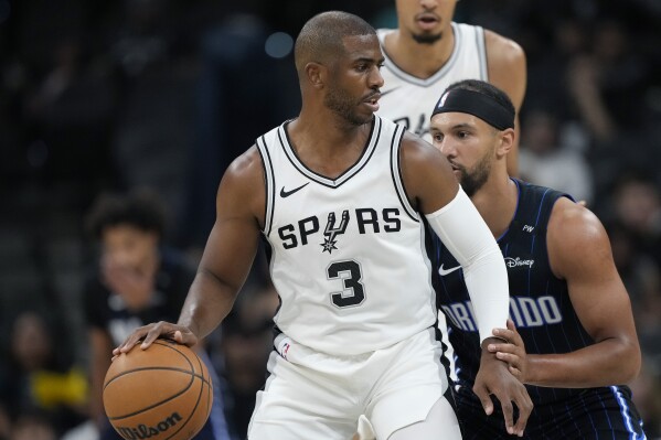 San Antonio Spurs guard Chris Paul (3) is defended by Orlando Magic guard Jalen Suggs, right, during the first half of a preseason NBA basketball game in San Antonio, Wednesday, Oct. 9, 2024. (AP Photo/Eric Gay)