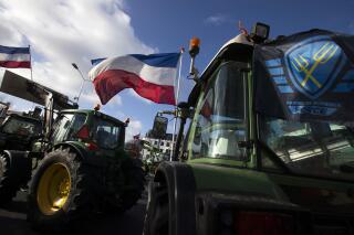 FILE - The Farmers Defense Force flag, right, and Dutch flags, fly in the wind on an intersection blocked by tractors in The Hague, Netherlands, Wednesday, Feb. 19, 2020. The Dutch government plans to drastically cut emissions of nitrogen pollution cleared a key hurdle Tuesday, May 2, 2023 when the European Union's executive arm gave the green light to farm buyout schemes worth nearly 1.5 billion euros ($1.65 billion). (AP Photo/Peter Dejong, File)