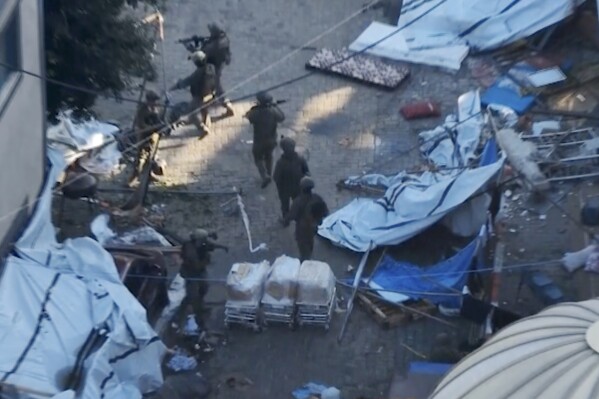 In this image taken from a video released by the Israeli Defense Forces on Tuesday, Nov. 15, 2023, Israeli soldiers walk in the area of Al-Shifa hospital in Gaza City. The Israeli military released footage on Tuesday that it said shows joint operational activity of two army brigades in its advancement on the ground in Gaza Strip. (Israel Defense Forces via AP)