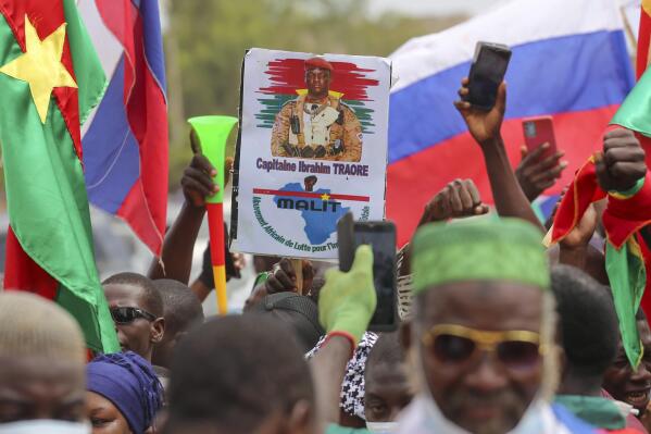 Supporters of Burkina Faso's latest coup leader Capt. Ibrahim Traore gather outside the National Assembly waving Burkina and Russian flags as Traore was appointed Burkina Faso's transitional president in Ouagadougou, Burkina Faso, Friday Oct. 14, 2022. (AP Photo/Kilaye Bationo)