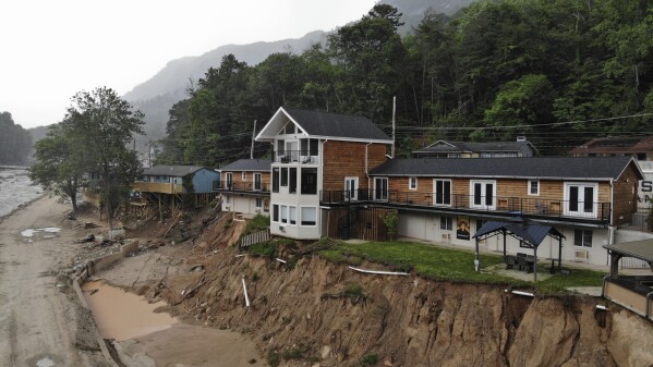 The Carter Lodge hangs precariously over the flood-scoured bank of the Broad River in Chimney Rock Village, N.C., on Tuesday, May 13, 2025. (AP Photo/Allen G. Breed)