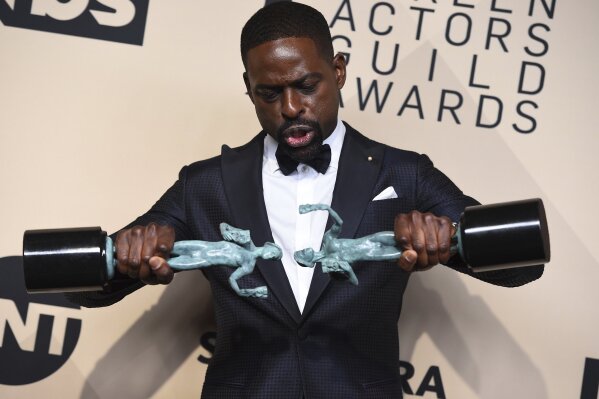 
              Sterling K. Brown, winner of the awards for outstanding performance by a male actor in a drama series for "This Is Us" and for outstanding performance by an ensemble in a drama series for "This Is Us", plays with his awards in the press room at the 24th annual Screen Actors Guild Awards at the Shrine Auditorium & Expo Hall on Sunday, Jan. 21, 2018, in Los Angeles. (Photo by Jordan Strauss/Invision/AP)
            