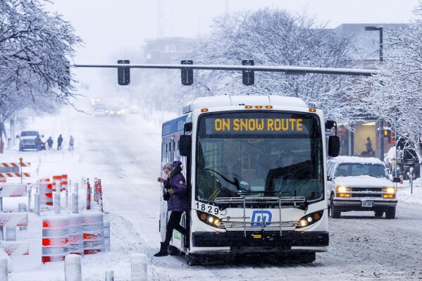 A rider gets off a bus on Harney Street during a snowstorm in downtown Omaha, Neb, on Tuesday, Jan. 9, 2024. (Chris Machian /Omaha World-Herald via AP)
