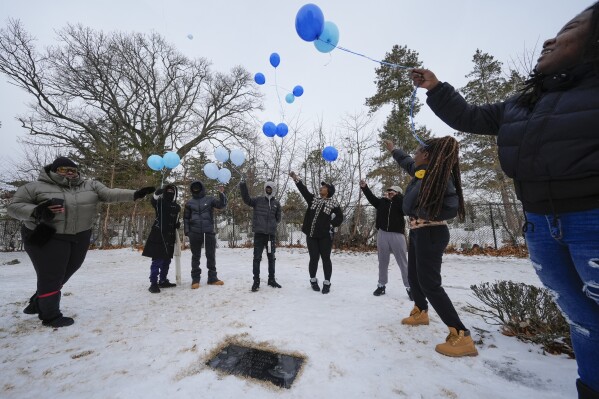 Family and friends of Jameek Lowery release balloons while visiting his grave in Garfield, N.J., Thursday, Jan. 18, 2024. From left are, Monique Lowery, Ron Jones, Zimere Jones, Timere Jones, Naomi Beal, Jamilyha Lowery, Jalea King and Shavontay McFadden. After praying and sharing memories and impassioned promises to find answers about Lowery’s death, an aunt exclaimed, “Say his name,” as they released the balloons. The mourners replied in unison: “Jameek Lowery.” (AP Photo/Seth Wenig)