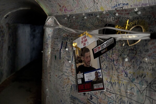 A poster depicting fallen Israeli soldier Itay Chen hangs in an installation representing a tunnel in the Gaza Strip, in Tel Aviv, Wednesday, May 8, 2024. Itay was killed in Hamas' attack on Oct. 7. But unlike scores of other families of soldiers killed that day, the Chens don't have a grave to visit because their son's remains are held captive in Gaza. The absence of a final resting place is being felt acutely now, as Israel marks its Memorial Day for fallen soldiers, when cemeteries are brimming with relatives mourning over the graves of their loved ones. (AP Photo/Maya Alleruzzo)
