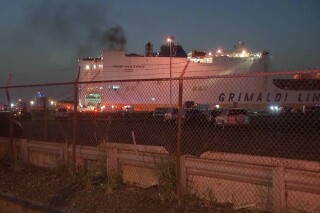 En esta imagen tomada de un video, humo saliendo de un barco de mercancías la madrugada del jueves 6 de julio de 2023 en el puerto de Newark, Nueva Jersey. Dos bomberos murieron combatiendo las llamas en el interior de un barco que transportaba 5.000 vehículos. (WABC-TV via AP)