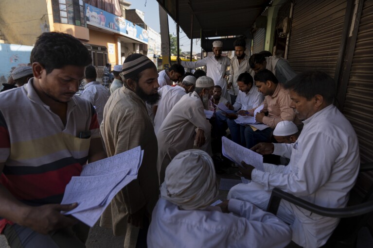 People check for their names in the voters' list as they arrive to vote during the second round of voting in the six-week-long national election in Nahal village near Meerut, in Uttar Pradesh, India, Friday, April 26, 2024. (AP Photo/Altaf Qadri)