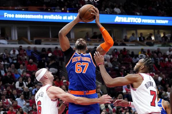 New York Knicks center Taj Gibson, center, rebounds the ball against Chicago Bulls guard Alex Caruso, left, and forward Troy Brown Jr. during the first half of an NBA basketball game Thursday, Oct. 28, 2021, in Chicago. (AP Photo/Nam Y. Huh)