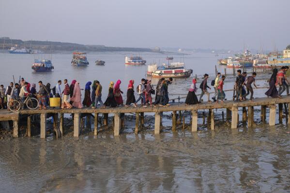 FILE - Workers walk to work at an export processing zone early in the morning after crossing the Mongla river in Mongla, Bangladesh, March 3, 2022. This Bangladeshi town stands alone to offer new life to thousands of climate migrants. (AP Photo/Mahmud Hossain Opu, File)