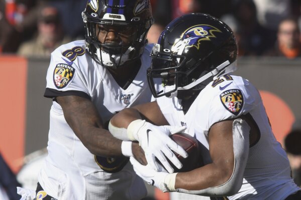 Baltimore Raven quarterback Lamar Jackson hands off to running back Mark Ingram during an NFL football game against the Cleveland Brown at FirstEnergy Stadium in Cleveland on Sunday, Dec. 22, 2019. (Warren Dillaway/The Star-Beacon via AP)