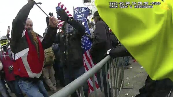 This still frame from Metropolitan Police Department body worn camera video shows Thomas Webster, in red jacket, at a barricade line at on the west front of the U.S. Capitol on Jan. 6, 2021, in Washington. Webster, a Marine Corps veteran and retired New York City Police Department Officer, is accused of assaulting an MPD officer with a flagpole. A number of law enforcement officers were assaulted while attempting to prevent rioters from entering the U.S. Capitol. (Metropolitan Police Department via AP)