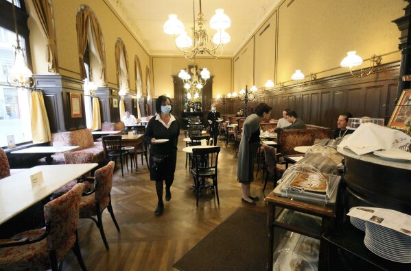 Waitresses with a protective mask serves guests at cafe 'Sperl' in Vienna, Austria, Friday, May 15, 2020. In Austria gastronomy may open again under certain conditions from Friday on. The Austrian government has moved to restrict freedom of movement for people, in an effort to slow the onset of the COVID-19 coronavirus. (AP Photo/Ronald Zak)