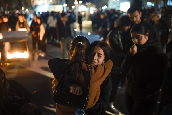 People hug as they wait in lines to light candles in the town of Kocani, North Macedonia, Sunday, March 16, 2025, following a massive fire in the nightclub early Sunday. (AP Photo/Armin Durgut)