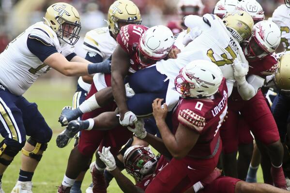 Florida State defenders, including defensive tackle Fabien Lovett (0), lift Georgia Tech running back Hassan Hall (3) off the ground as he tries to runs the ball in the second quarter of an NCAA college football game Saturday, Oct. 29, 2022, in Tallahassee, Fla. (AP Photo/Phil Sears)