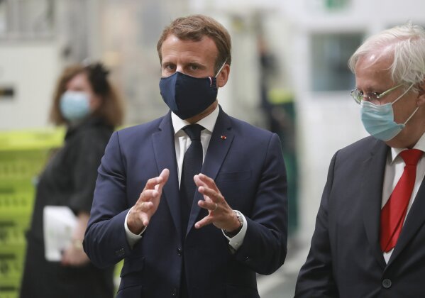 French President Emmanuel Macron, center, wearing a protective face mask, visits a factory of manufacturer Valeo in Etaples, , northern France, Tuesday May 26, 2020. Emmanuel Macron announced a 8 billion euro ($8.8 billion) plan Tuesday to save the country's car industry from huge losses wrought by virus lockdowns, including a big boost for electric vehicles. The plan includes government subsidies for car buyers and longer-term investment in innovative technology, especially in battery-powered cars. (Ludovic Marin, Pool via AP)