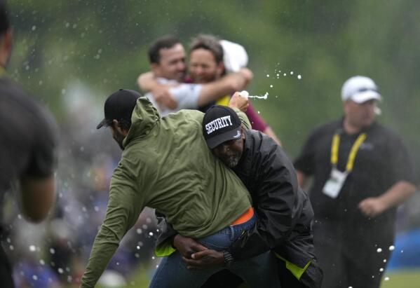 Canadian professional golfer Adam Hadwin, left, is stopped by a security guard while he tries to celebrates with Nick Taylor, of Canada, after Taylor won the Canadian Open golf tournament in Toronto, Sunday, June 11, 2023. (Andrew Lahodynskyj/The Canadian Press via AP)