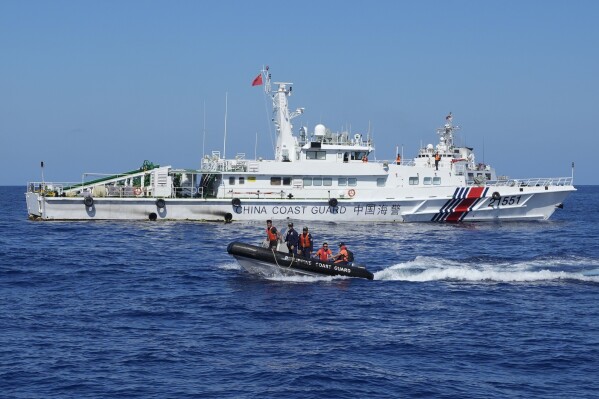 Philippine coast guard personnel on a rubber boat pass by a Chinese coast guard ship after conducting medical treatment to injured crew members of Philippine resupply vessel Unaizah May 4 which got hurt during a water canon incident in the disputed South China Sea Tuesday, March 5, 2024. Chinese and Philippine coast guard vessels collided in the disputed South China Sea and four Filipino crew members were injured in high-seas confrontations Tuesday as Southeast Asian leaders gathered for a summit that was expected to touch on Beijing's aggression at sea. (AP Photo/Aaron Favila)