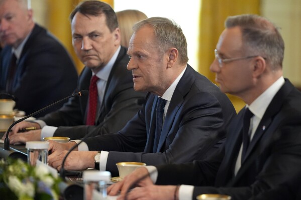FILE - Polish President Andrzej Duda, right, and Polish Foreign Minister Radek Sikorski, second from left, listen as Polish Prime Minister Donald Tusk, second from right, speaks during a meeting with President Joe Biden in the East Room of the White House, Tuesday, March 12, 2024, in Washington. Poland’s Foreign Ministry said Wednesday, March 13, 2024, that it is cutting short the missions of 50 of the nation’s ambassadors as the new pro-European Union government is aiming to improve the functioning and the professionalism of the missions at a challenging time. (AP Photo/Andrew Harnik, File)