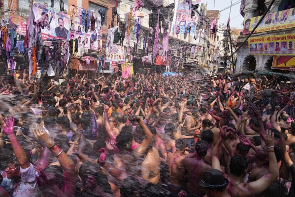Revelers, faces smeared with colored powder, dance during celebrations to mark Holi, the Hindu festival of colors in Prayagraj, northern Uttar Pradesh state, India, Monday March 25, 2024. (AP Photo/Rajesh Kumar Singh)
