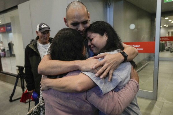 Sean Ours, center, who lives in Alexandria, VA, and Emily Reid, right who lives in Raleigh, NC, embrace for the first time their biological mother Sara Melgarejo upon their arrival at the airport in Santiago, Chile, Sunday, Feb. 18, 2024. The siblings' trip was organized by Connecting Roots, an organization that helps reunite with their Chilean biological families children who were taken to be put up for adoption during the dictatorship of Gen. Augusto Pinochet. (AP Photo/Esteban Felix)