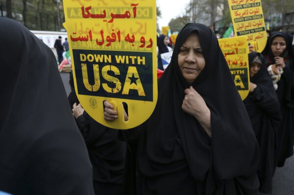 A demonstrator holds an anti-U.S. placard during an annual rally outside the former U.S. Embassy in Tehran, Iran, Monday, Nov. 4, 2019. Reviving decades-old cries of "Death to America," Iran on Monday marked the 40th anniversary of the 1979 student takeover of the U.S. Embassy in Tehran and the 444-day hostage crisis that followed as tensions remain high over the country's collapsing nuclear deal with world powers. The Persian on top of the placard is a quotation of the Supreme Leader Ayatollah Ali Khamenei which reads: "U.S. is on the verge of annihilation." (AP Photo/Vahid Salemi)