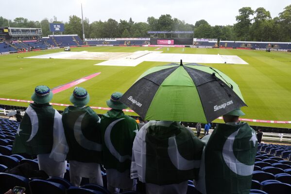 Fans in the stands shelter from the rain under umbrellas ahead of the third IT20 match at Sophia Gardens, Cardiff, Tuesday May 28, 2024. Bad weather forced the abandonment of the T20 match between England and Pakistan in Cardiff. (Nick Potts/PA via AP)