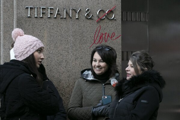 Sophie Forshaw, left, and Kelly Fenna, second from left, of Liverpool,  England, stand in front of Tiffany's flagship store with their purchases,  Monday, Nov. 25, 2019 in New York. French luxury group