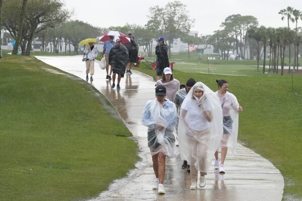Spectators exit the course as heavy rain delays the final round of the Cognizant Classic golf tournament, Sunday, March 3, 2024, in Palm Beach Gardens, Fla. (AP Photo/Marta Lavandier)