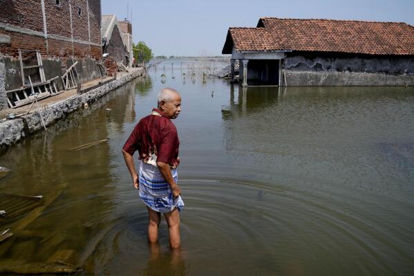 FILE - Sukarman walks on a flooded pathway outside his house in Timbulsloko, Central Java, Indonesia, July 30, 2022. Secretary-General Antonio Guterres warned Tuesday, Feb. 14, 2023, that even if global warming is "miraculously" limited to 1.5 degrees Celsius (2.7 degrees Fahrenheit), there will still be a sizable sea level rise. (AP Photo/Dita Alangkara, File)