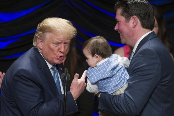 President Donald Trump reacts after kissing Hudson Nash, being held by father Andrew Nash, as Trump speaks about kidney health at the Ronald Reagan Building and International Trade Center, Wednesday, July 10, 2019, in Washington. (AP Photo/Alex Brandon)