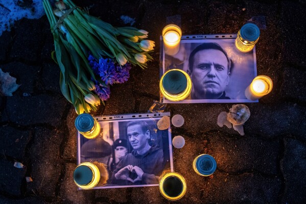 Photos of Russian opposition leader Alexei Navalny, with flowers and candles are laid on a ground in front of the Russian embassy in Vilnius, Lithuania, Friday, Feb. 16, 2024. Navalny, who crusaded against official corruption and staged massive anti-Kremlin protests as President Vladimir Putin's fiercest foe, died Friday in the Arctic penal colony where he was serving a 19-year sentence, Russia's prison agency said. He was 47. (AP Photo/Mindaugas Kulbis)