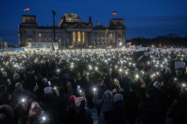 FILE - People hold up their cell phones as they protest the far-right Alternative for Germany, or AfD party, and right-wing extremism in front of the parliament building in Berlin, Germany, Jan. 21, 2024. Millions of Germans have joined rallies all over the country for weeks in a row, attending events with slogans such as "Never Again is Now." The protesters have been alarmed by the AfD's policies and its growing popularity. (AP Photo/Ebrahim Noroozi, File)