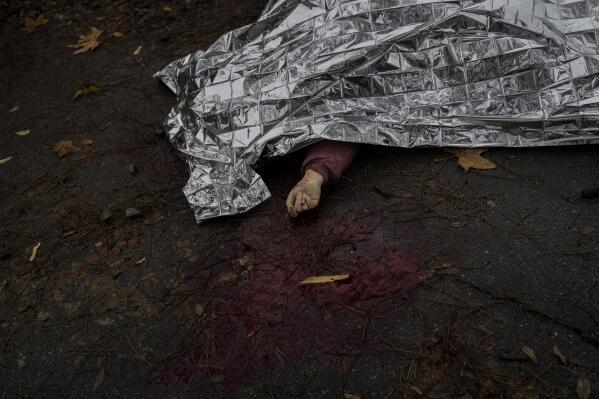 The body of a woman killed during a Russian attack is covered with an emergency blanket before being transported to the morgue in Kherson, southern Ukraine, Friday, Nov. 25, 2022. A barrage of missiles struck the recently liberated city of Kherson for the second day Friday in a marked escalation of attacks since Russia withdrew from the city two weeks ago following an eight-month occupation. (AP Photo/Bernat Armangue)