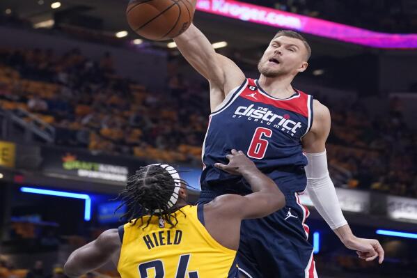 Washington Wizards' Kristaps Porzingis (6) dunks against Indiana Pacers' Buddy Hield (24) during the first half of an NBA basketball game Wednesday, Oct. 19, 2022, in Indianapolis. (AP Photo/Michael Conroy)