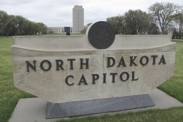 FILE - The North Dakota Capitol tower rises in the background behind a stone sign, April 19, 2012, in Bismarck, N.D. North Dakota will hold Republican presidential caucuses on Monday, March 4, 2024, the last chance for former President Donald Trump’s rivals for the GOP nomination to slow his momentum heading into Super Tuesday on March 5, the biggest day of the primary campaign. (AP Photo/Dale Wetzel, File)