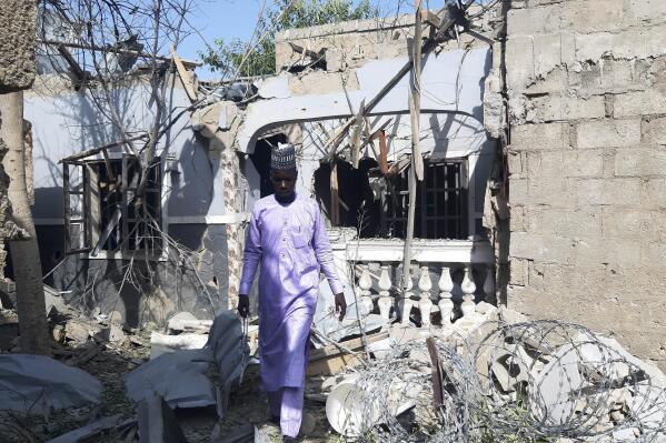 A man walks past a scene of an explosion in Maiduguri, Nigeria, Thursday Dec. 23, 2021. An unconfirmed number of persons were killed on Thursday by bomb explosions carried out by extremist rebels in northeast Nigeria, according to witnesses. (AP Photo/Jossy Ola)