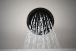 FILE - In this Aug. 12, 2020, file photo water flows from a showerhead in Portland, Ore. The Trump administration on Wednesday, Dec. 16, relaxed a regulation restricting water flow from showerheads, a pet peeve of President Donald Trump who complained that he needed more water to make his hair “perfect.” (AP Photo/Jenny Kane, File)
