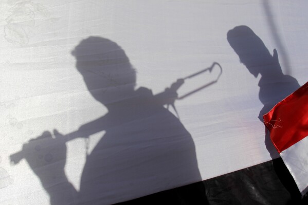 FILE - The shadow of Shiite rebels, known as Houthis, are cast on a large representation of the Yemeni flag as they attend a demonstration against an arms embargo imposed by the U.N. Security Council on Houthi leaders, in Sanaa, Yemen, on April 16, 2015. A delegation from Yemen's Houthi rebels have flown into Saudi Arabia for talks with the kingdom on potentially ending the yearslong war tearing at the Arab world's poorest nation, officials say. (AP Photo/Hani Mohammed, File)