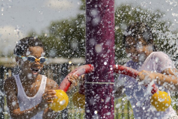 Jase Howard plays in the water with his cousin Denim Howard at the Ormond Spray Park in Destrehan, La., on Tuesday, June 27, 2023. (Brett Duke/The Advocate via AP)