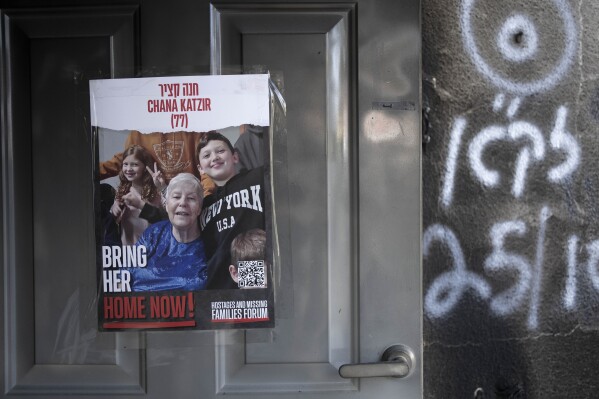 A poster calling for the release of Chana Katzir is taped to the door of her home in Kibbutz Nir Oz, on Nov. 21, 2023. Katzir was kidnapped by Hamas militants on Oct. 7, from her home and taken to the Gaza Strip. She has since been freed. An Associated Press review of hundreds of messages shared among Nir Oz residents, security camera footage and Hamas instruction manuals show the group planned ahead of time to target civilians. (AP Photo/Maya Alleruzzo)