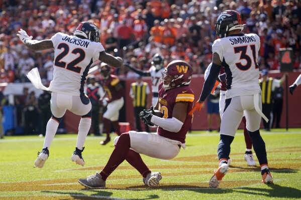 Washington Commanders tight end Logan Thomas, center, catches a touchdown pass as he is hit by Denver Broncos safety Kareem Jackson (22) in the first half of an NFL football game Sunday, Sept. 17, 2023, in Denver. Jackson was ejected for his helmet-to-helmet hit on Thomas. (AP Photo/David Zalubowski)