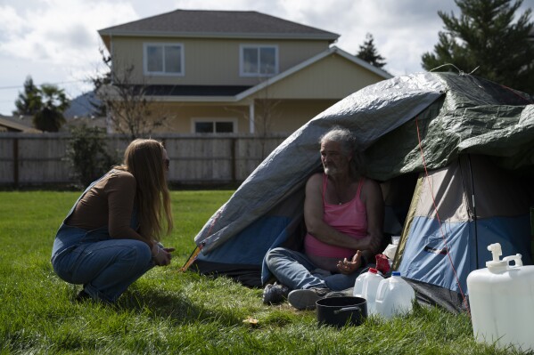 Cassy Leach, a nurse, who leads a group of volunteers who provide food, medical care and other basic goods to the hundreds of homeless people living in the parks, talks to Kimberly Marie, who is homeless and camping in Fruitdale Park on Thursday, March 21, 2024, in Grants Pass, Ore. (AP Photo/Jenny Kane)
