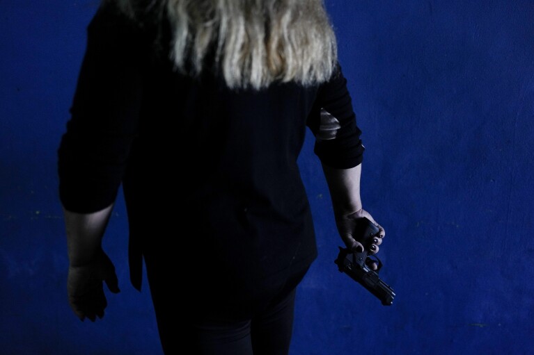 A resident who did not want to be identified shows the gun she keeps at her home for self-defense as she poses for a photo in Rosario, Argentina, Monday, April 8, 2024. The homicide rate is five times the national average in Rosario. (AP Photo/Natacha Pisarenko)
