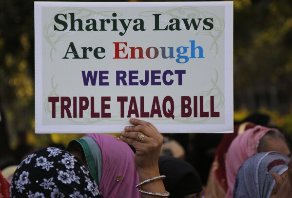 
              FILE - In this Jan. 7, 2018 file photo, an Indian Muslim woman holds a placard during a protest against a new draft law aimed at banning "Triple Talaq," a Muslim practice of instant ...