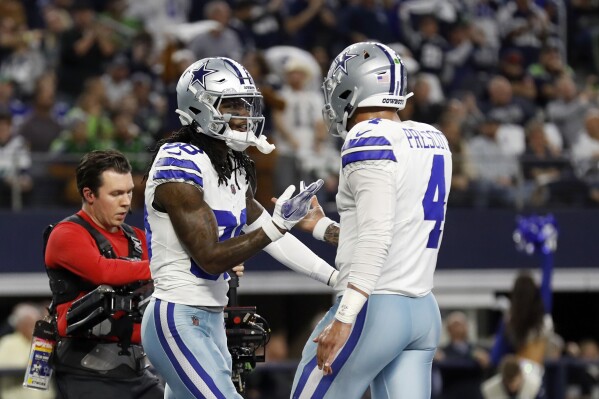 Dallas Cowboys' CeeDee Lamb, left, and Dak Prescott (4) celebrate after Lamb's touchdown catch in the first half of an NFL football game against the Seattle Seahawks in Arlington, Texas, Thursday, Nov. 30, 2023. (AP Photo/Roger Steinman)