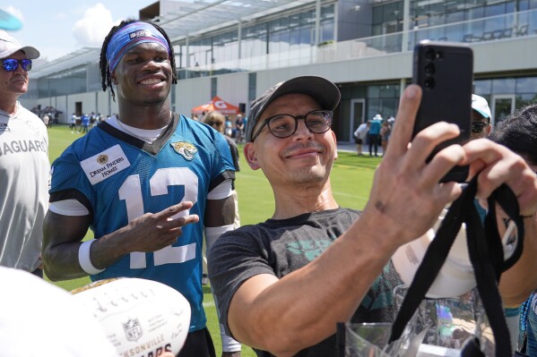 Jacksonville Jaguars wide receiver Travis Hunter (12) poses for a photo with a fan during practice at NFL football minicamp, Wednesday, June 11, 2025, in Jacksonville, Fla. (AP Photo/John Raoux)