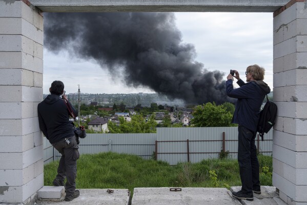 Foreign journalists report from an observation point while smoke rises after a Russian attack in Kharkiv, Ukraine, Friday, May 17, 2024. (AP Photo/Evgeniy Maloletka)
